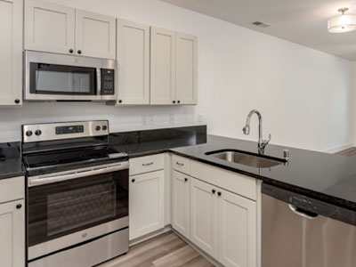 A clean kitchen with new appliances and bar stools at the counter