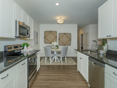 A clean kitchen with new appliances and bar stools at the counter