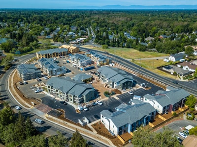 An aerial view of the apartment complex shows buildings surrounded by many trees